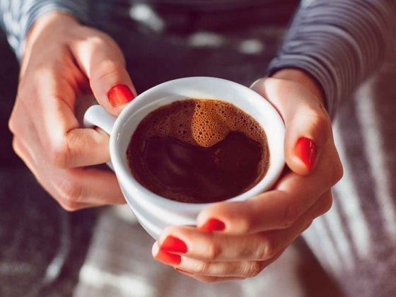 Frauenhaende und eine Tasse schwarzer Kaffee