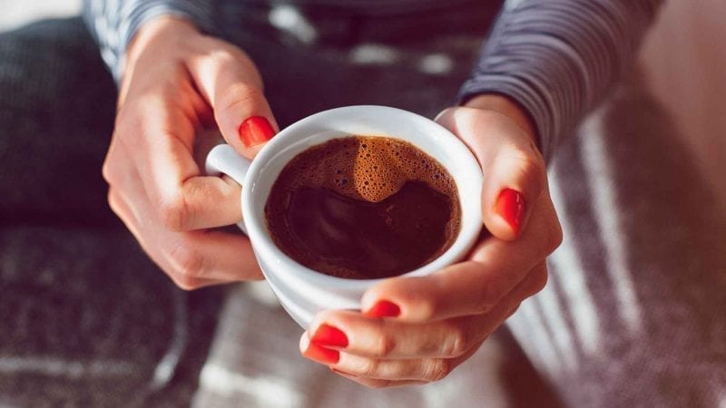 Frauenhaende und eine Tasse schwarzer Kaffee