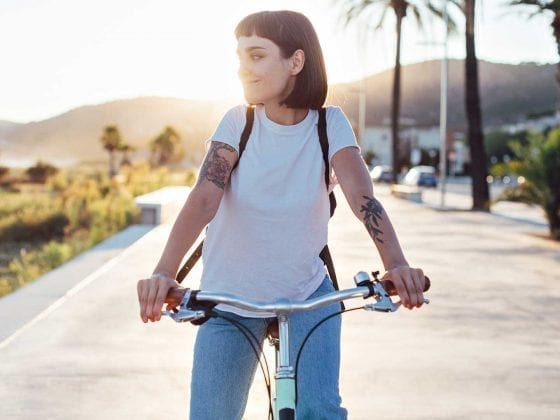 Eine junge Frau fährt auf einem Fahrrad an einer Strandpromenade