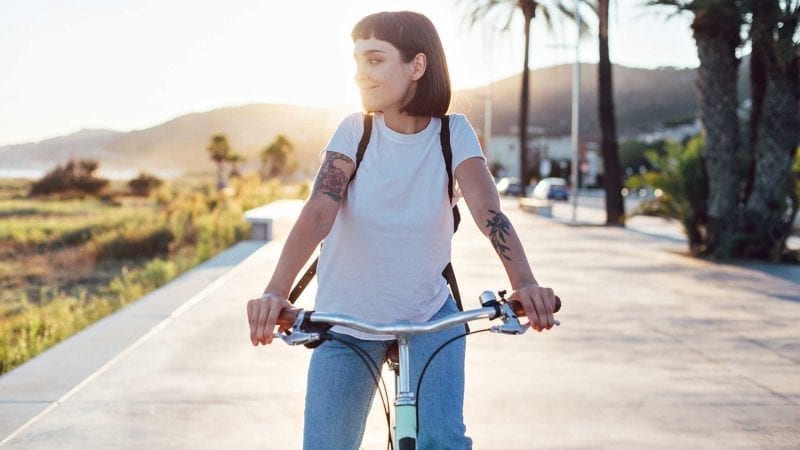 Eine junge Frau fährt auf einem Fahrrad an einer Strandpromenade