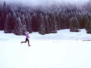 Joggerin läuft durch eine schneelandschaft