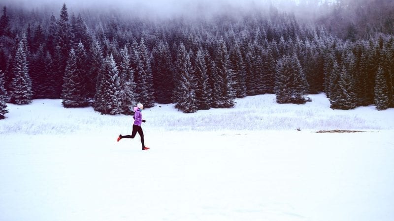 Joggerin läuft durch eine schneelandschaft