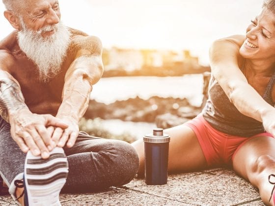 Aelterer Sportler und junge Sportlerin bei Dehnuebungen