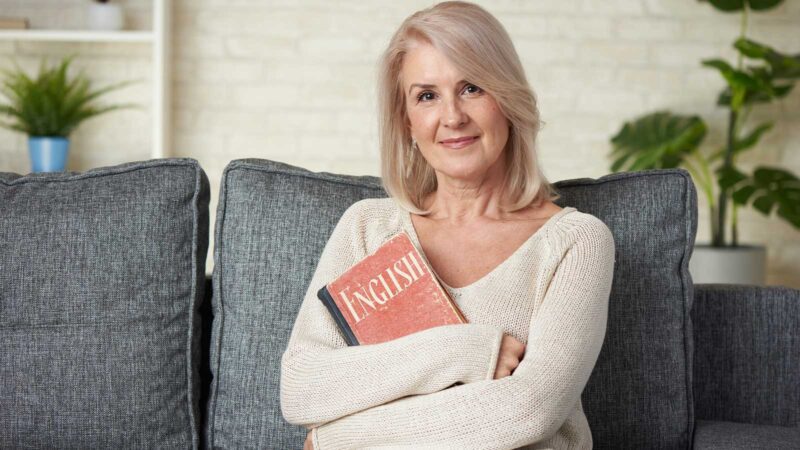 frau sitzt auf sofa mit buch