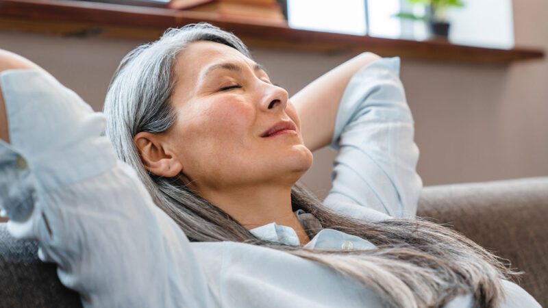 Eine Frau entspannt auf dem Sofa. Vitalstoffkombinationen unterstuetzen unsere Balance-