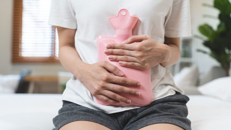 Frau mit Wärmflasche am Bauch